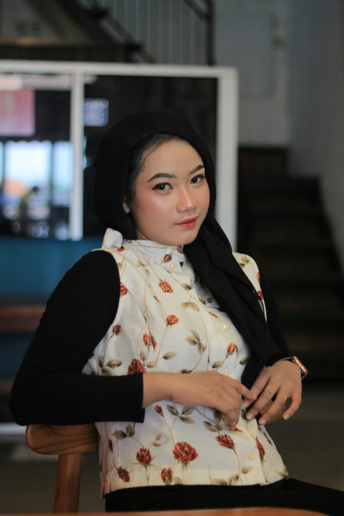 Charming portrait of a woman in a floral top, sitting indoors and looking at the camera. | cheap clothes