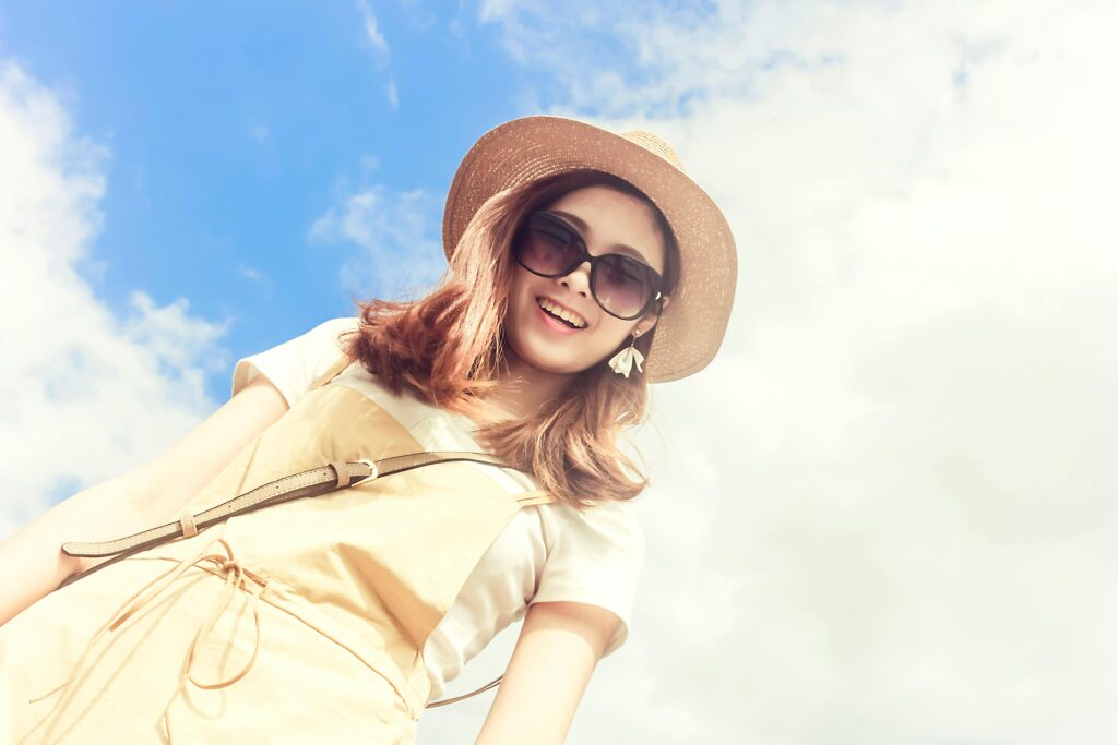Smiling young woman in straw hat and sunglasses against a clear blue sky. Perfect summer style portrait. | cheap clothes